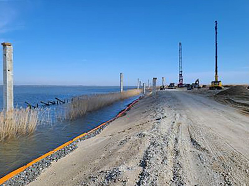 sandy shoreline on water with turbidity curtain