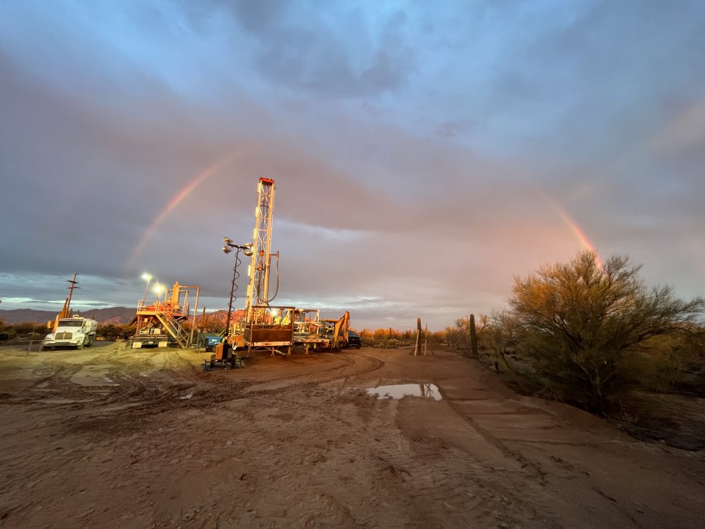 water well drill in the distance with a rainbow over the worksite