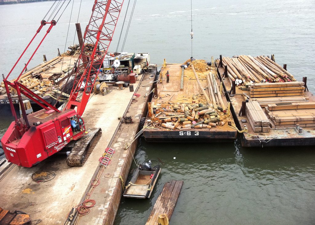 construction management project on waterfront with crane lifting wood