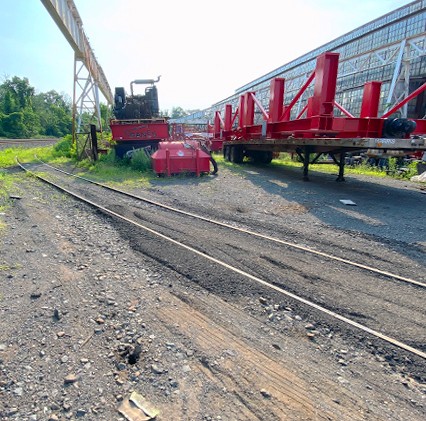 view of building windows on right, red steel structure, equipment and train tracks on left