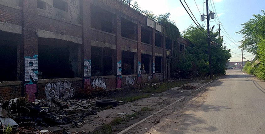 view of abandoned building on left and street going into distance
