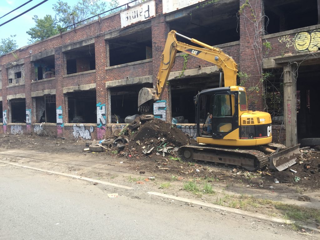 Excavator in front of abandoned building