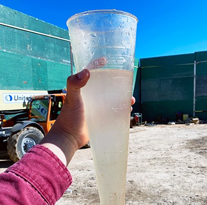 hand holding up large container of clean well water sample