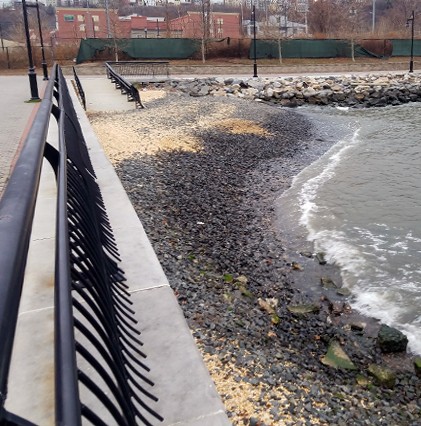 rocky shoreline by water and walkway structure on left