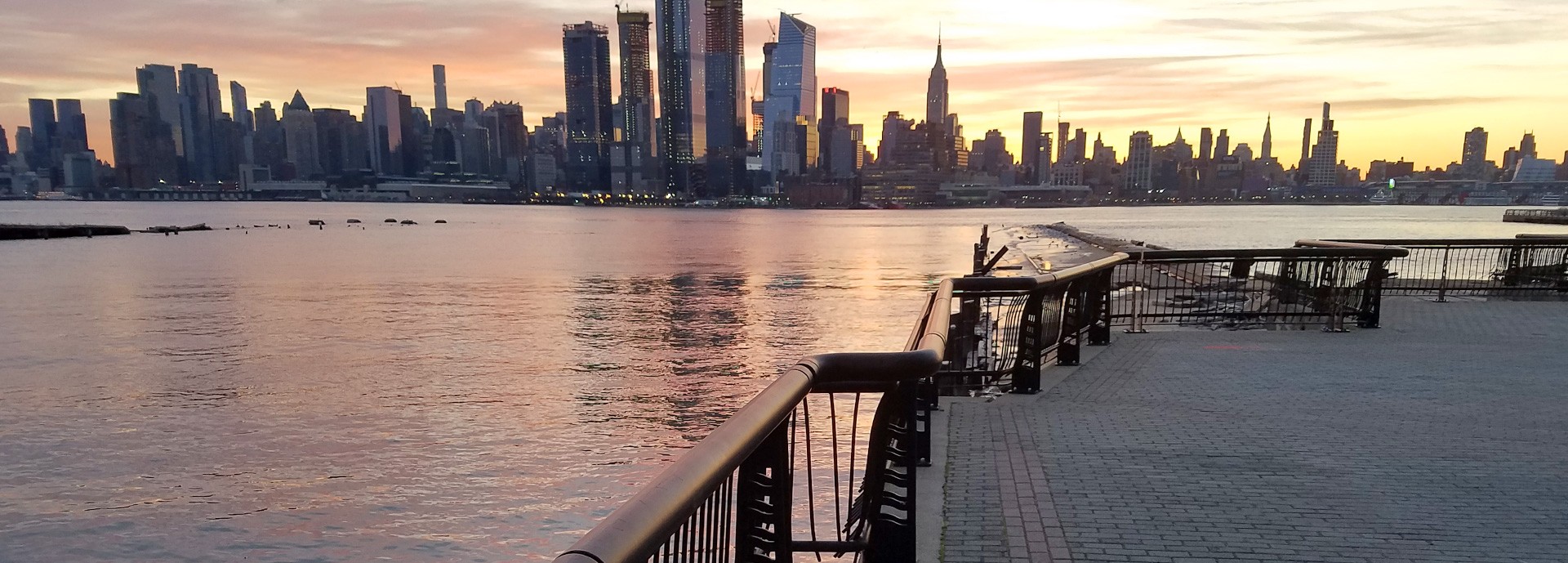 pier on hudson river at sunset with skyline in background