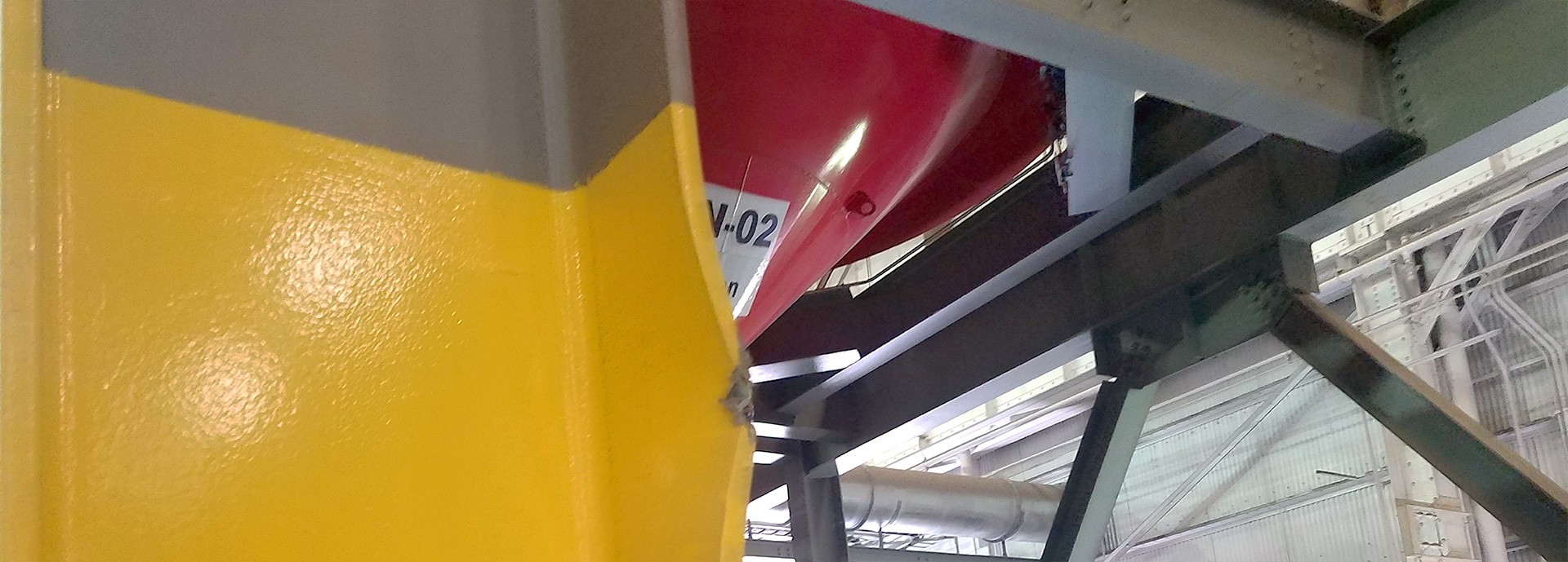closeup of girder painted yellow in processing facility with girders in the background