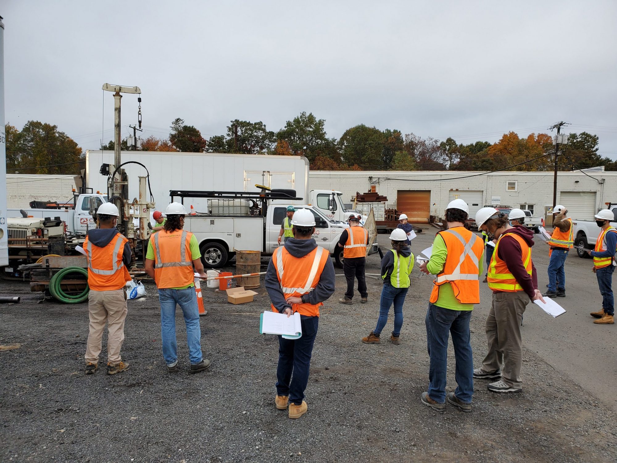workers in safety gear listing to a site meeting