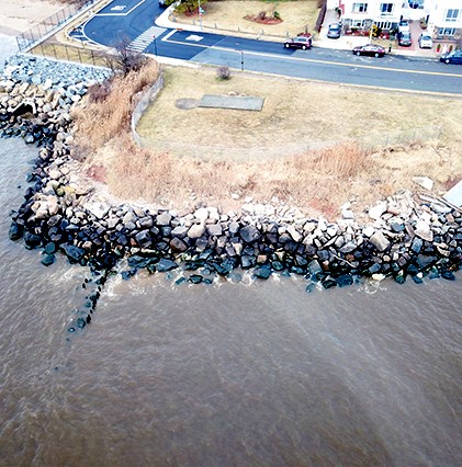 aerial of rocky shoreline and water with houses close by
