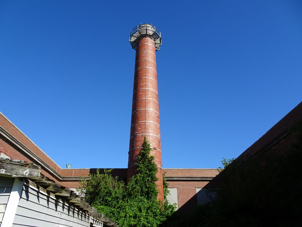 brick tower against blue sky with brick building walls below