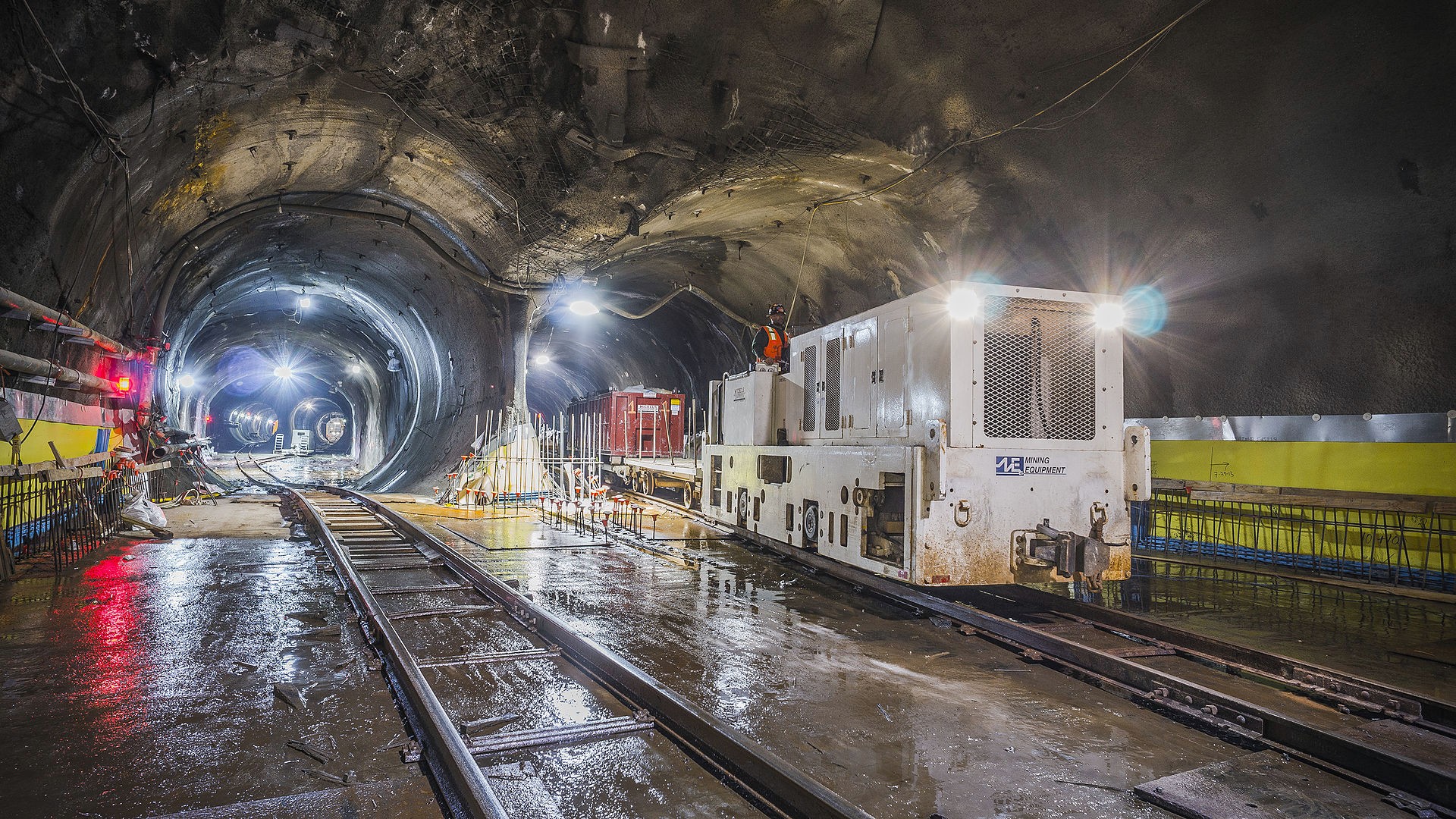 subway tunnel with subway cars and tracks with workers around the work site
