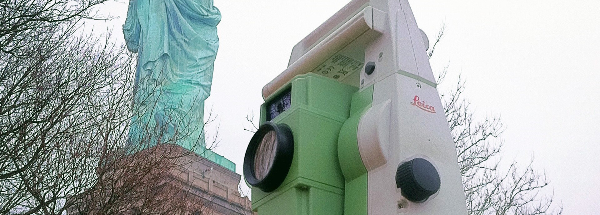 close up of survey equipment in front of the statue of liberty