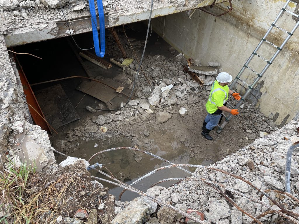 worker in large pit by a ladder