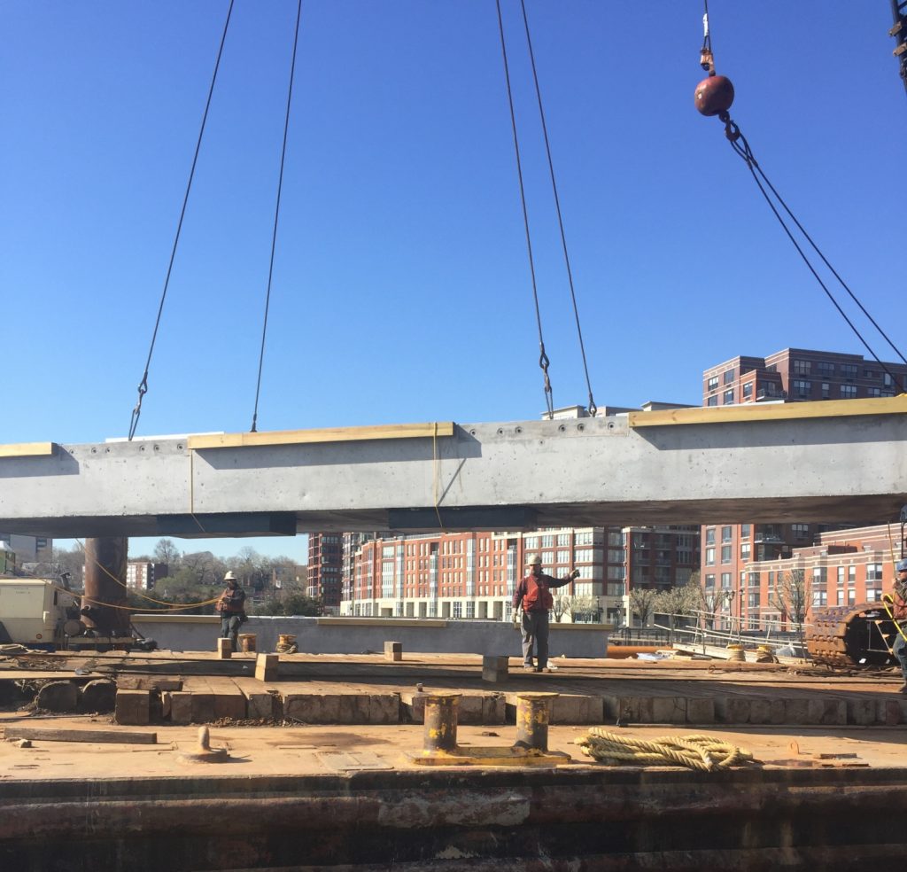 steel beam being lifted by crane on pier