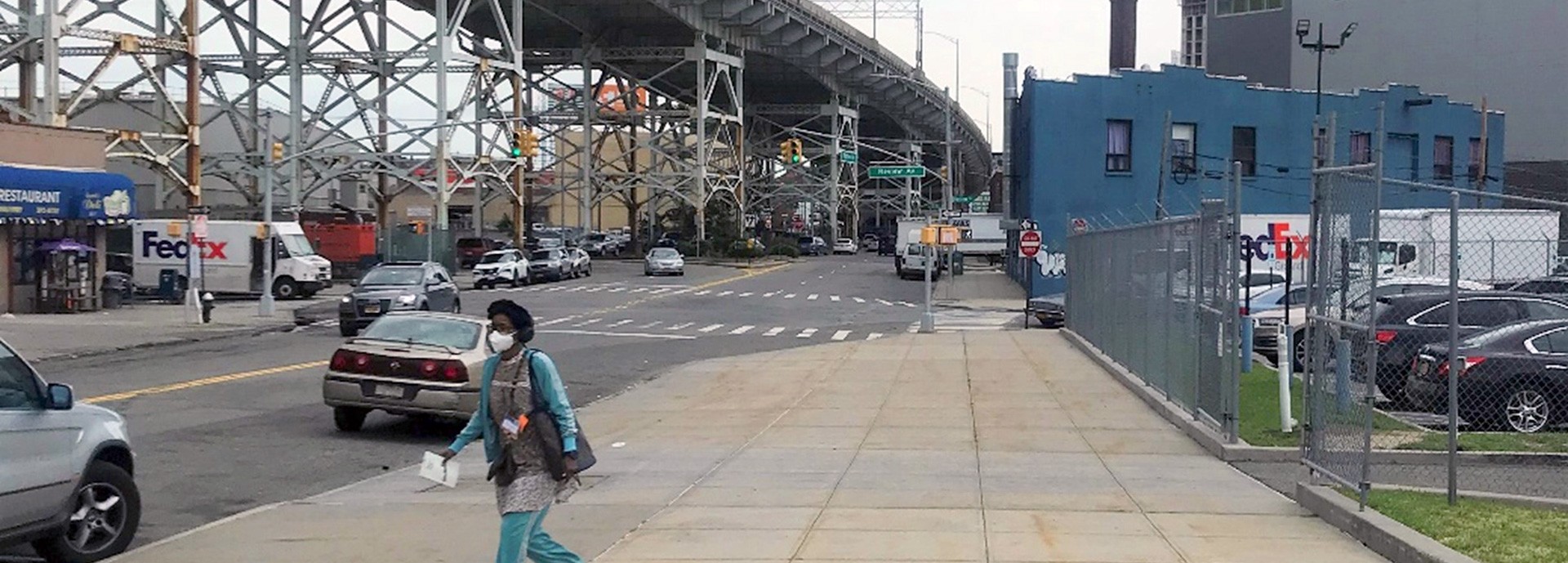 view from sidewalk under large bridge in the nyc area and woman walking on sidewalk
