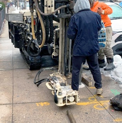 workers on sidewalk with geotechnical equipment
