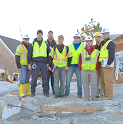 group of workers in bright vests and hardhats on scene of destroyed houses on jersey shore