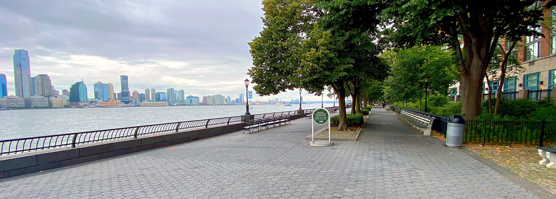 view of boardwalk pier in battery park with trees on right and water on left