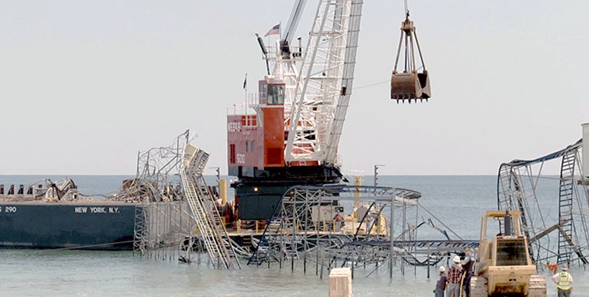 crane working on damaged pier and rollercoaster on jersey shore