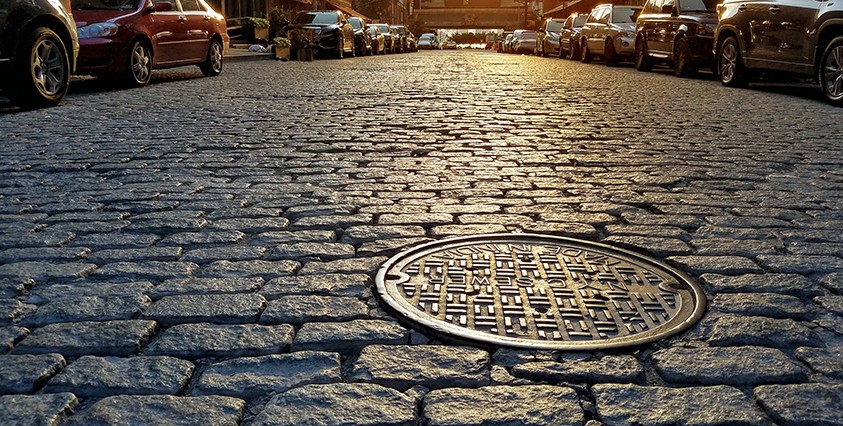 close up of a manhole cover on a cobblestone road in nyc
