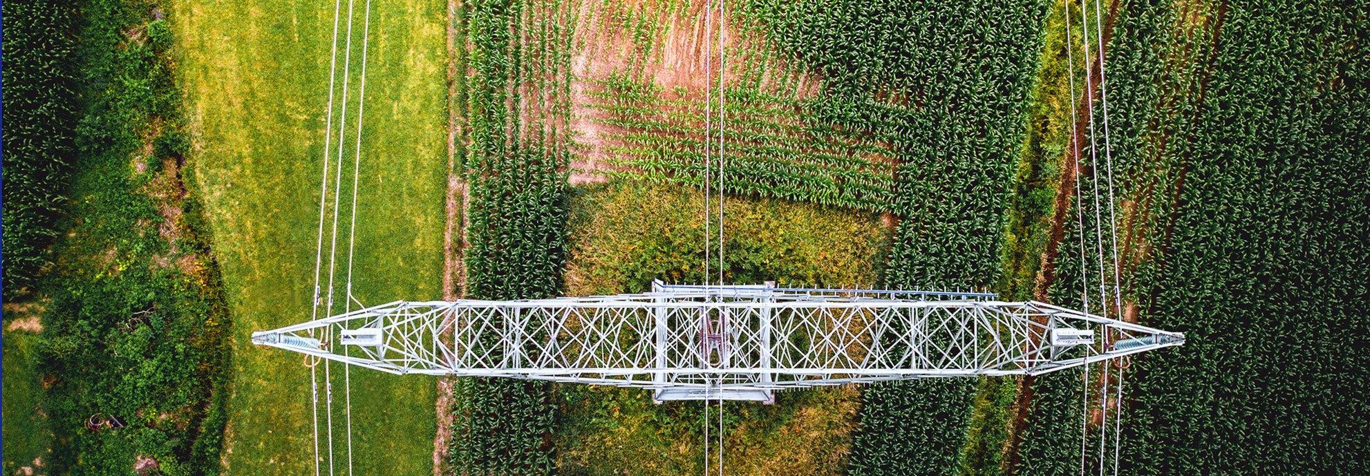 aerial view of electrical tower and wires in a green field