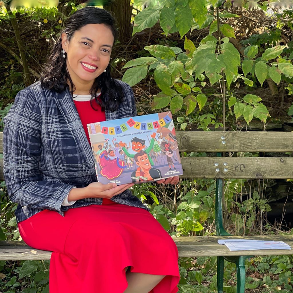 olga abinader posing with childrens book on bench outside
