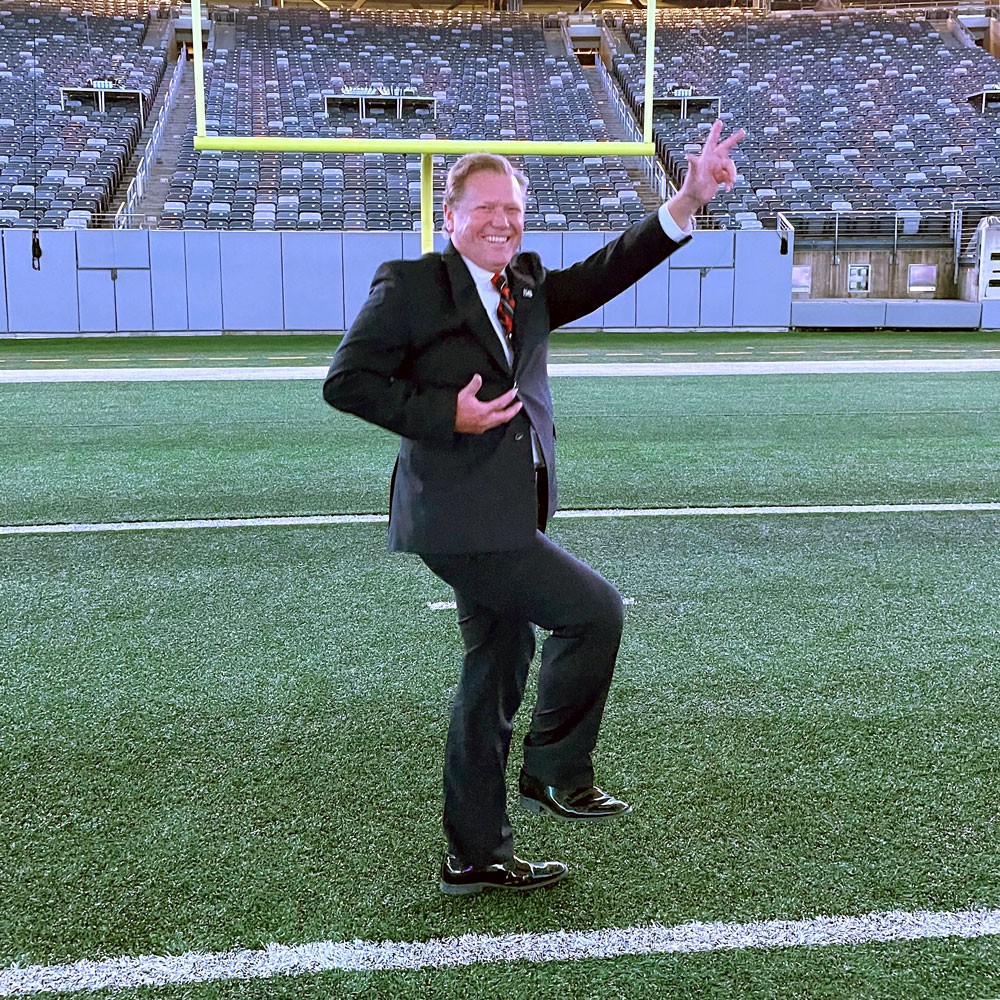 andy raichle posing with football on football field at metlife stadium