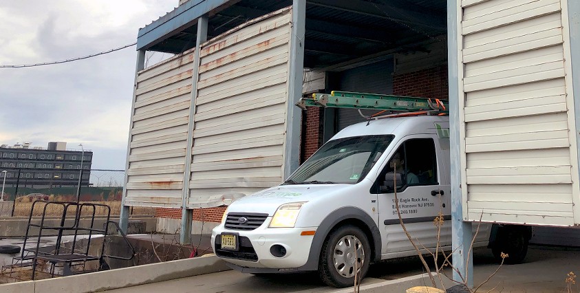 white van emerging from a metal warehouse hut on project site